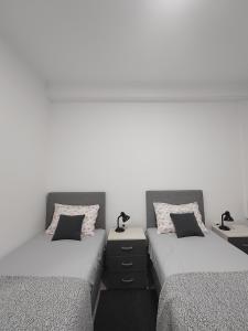 2 Einzelbetten in einem Zimmer mit weißen Wänden in der Unterkunft Apartman Centar Ivanjica in Ivanjica