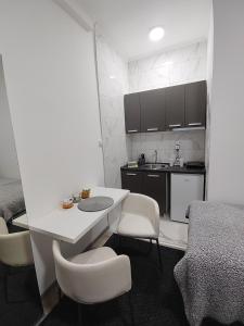 una pequeña cocina con mesa blanca y sillas en Apartman Centar Ivanjica en Ivanjica
