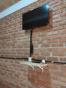 TV de pantalla plana colgada en una pared de ladrillo en Pousada do Chicó, en São Roque de Minas