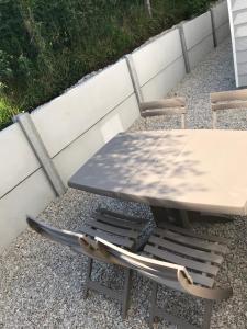 ein Picknicktisch und zwei Stühle neben einer Wand in der Unterkunft Les oiseaux de la Slack in Ambleteuse