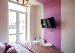 1 dormitorio con TV en una pared púrpura en Casa Esmeralda, en Valparaíso