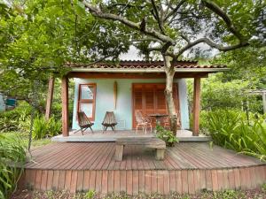 a small house with a deck with a table and chairs at Morada das Bromélias in Torres