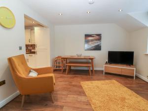 a living room with a chair and a tv and a table at Y Enciliad in Rhosneigr