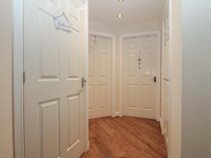 a hallway with white doors and wooden floors at Y Enciliad in Rhosneigr