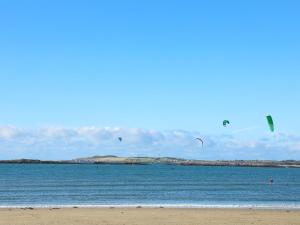 a group of kites flying over the water on a beach at Y Enciliad in Rhosneigr