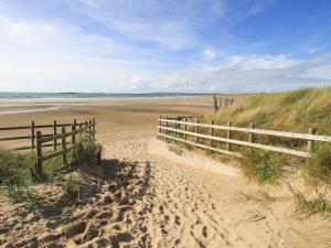 a sandy beach with a wooden fence and a wooden at Y Enciliad in Rhosneigr