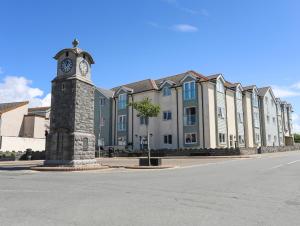 una torre dell'orologio di fronte a un grande edificio di Y Enciliad a Rhosneigr