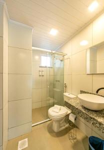 y baño con aseo, lavabo y ducha. en Apartamento com garagem no Centro de Guaramiranga, en Guaramiranga