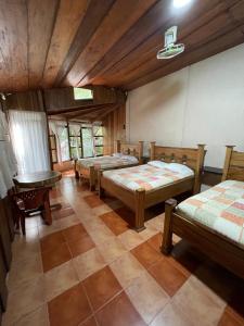 Habitación con 4 camas y mesa. en Hotel Ecológico Cabañas del Lago, en El Estor