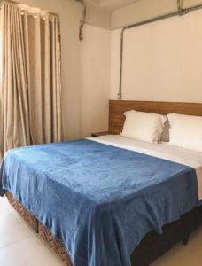 een slaapkamer met een groot bed en een blauwe deken bij Apartamento com garagem no Centro de Guaramiranga in Guaramiranga
