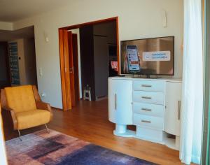 uma sala de estar com uma cómoda com uma televisão e uma cadeira em ROTA - Opo airport house em Maia