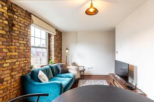 un soggiorno con divano blu e muro di mattoni di Charming Shoreditch Apartment a Londra