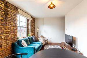 a living room with a blue couch and a brick wall at Charming Shoreditch Apartment in London