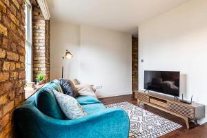 sala de estar con sofá azul y TV en Charming Shoreditch Apartment, en Londres