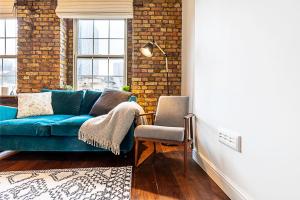 sala de estar con sofá azul y silla en Charming Shoreditch Apartment, en Londres