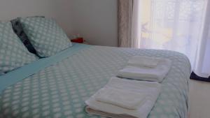 uma cama com toalhas dobráveis com uma janela em Morena Villa Familiale em Bompas
