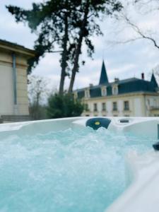 a tub full of water with a building in the background at Le Château d Hardricourt in Hardricourt