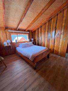 een slaapkamer met een bed in een houten hut bij Kumewe Lodge in Panguipulli