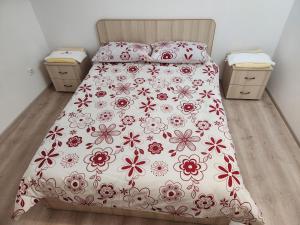 a bed with a red and white bedspread with flowers at Dream House Caransebeș in Caransebeş