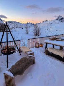 un patio cubierto de nieve con mesa y chimenea en Sundet Lofoten Holiday House en Sund