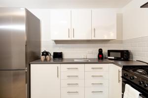a kitchen with white cabinets and a stainless steel refrigerator at Suite 6 - Double Room in the Heart of Oldham in Oldham