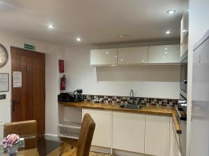 a kitchen with white cabinets and a table and a clock at Pine cottage with private hot tub in Upper Hulme