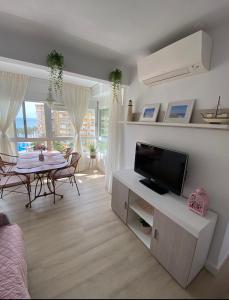 ein Wohnzimmer mit einem TV und einem Tisch mit Stühlen in der Unterkunft Casa Rosa in Algarrobo-Costa