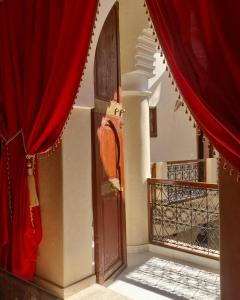 una puerta abierta en una habitación con cortinas rojas en Labigarade riad, en Marrakech