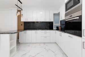 a kitchen with white cabinets and black appliances at Modern Apartment Bergantin in Torrevieja