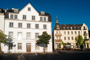zwei hohe weiße Gebäude mit einem Baum in einer Straße in der Unterkunft YokoLou - Design-Apartments in Koblenz