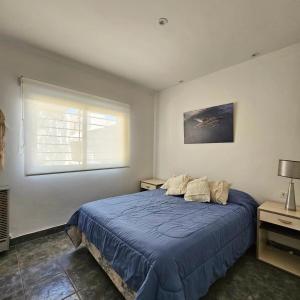 Un dormitorio con una cama azul y una ventana en OlaLasGrutas Casa 4ta Bajada en Las Grutas