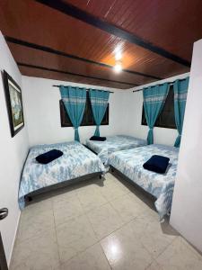 - 2 lits dans une chambre dotée de rideaux bleus dans l'établissement Finca Numantia, à Santa Rosa de Cabal