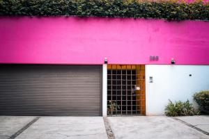 a pink building with two garage doors in front at Hostal Cuija Coyoacan Berlin 268 Coyoacan in Mexico City