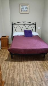 Una cama con una manta morada encima. en habitaciones, restaurante asador el puente Galdames en San Pedro de Galdames