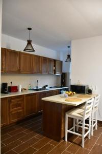 a kitchen with wooden cabinets and a kitchen island with chairs at Pensiunea Crenguța Fermecată in Cladova