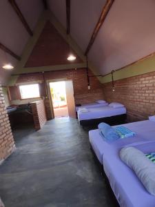 um quarto com três camas e uma parede de tijolos em Pousada do Chicó em São Roque de Minas