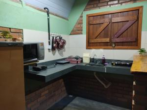 a kitchen with a counter with a sink and a microwave at Pousada do Chicó in São Roque de Minas