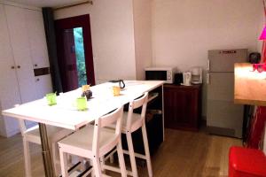 a kitchen with a white island with chairs and a refrigerator at Pretty house with double terrace near the ocean in Moliets-et-Maa