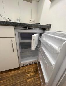 un frigorifero vuoto con la porta aperta in una cucina di Medienhafen Apartment direkt am Zentrum a Dusseldorf
