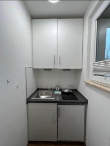 a kitchen with white cabinets and a sink at Medienhafen Apartment direkt am Zentrum in Düsseldorf