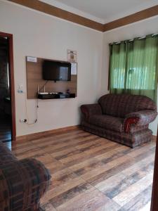 uma sala de estar com um sofá e uma televisão em Chácara talismã 3 em Olímpia