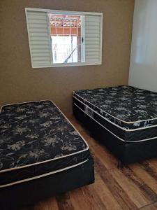 duas camas sentadas em um quarto com janela em Chácara talismã 3 em Olímpia