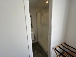 a bathroom with a shower and a toilet and a chair at The Raglan Harbourside Hutch in Raglan
