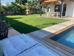 eine Holzterrasse neben einem Garten mit einem Pool in der Unterkunft Villa bassin Arcachon Gujan-Mestras in Gujan-Mestras