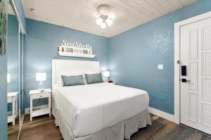 ein Schlafzimmer mit einem weißen Bett und einer blauen Wand in der Unterkunft Seashells Getaway - Boat Slip, Ramp, Pool in Marathon
