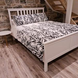 - un lit blanc avec une couette en noir et blanc dans l'établissement Luxury 300yr old Irish thatch cottage close to sea, à Rush