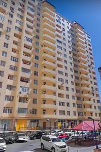 Premium Apartments Baku في باكو: عمارة سكنية كبيرة فيها سيارات تقف في موقف للسيارات