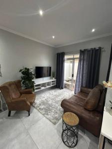 a living room with a brown couch and a television at RR Luxury apartment in Welkom