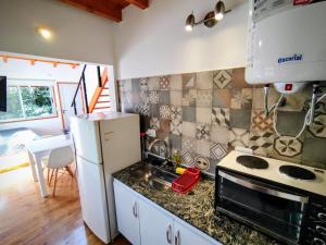 a kitchen with a white refrigerator and a sink at Cedro Azul in La Cumbre
