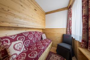 Habitación pequeña con sofá y silla en Hotel Columbia & Spa, en Cortina dʼAmpezzo